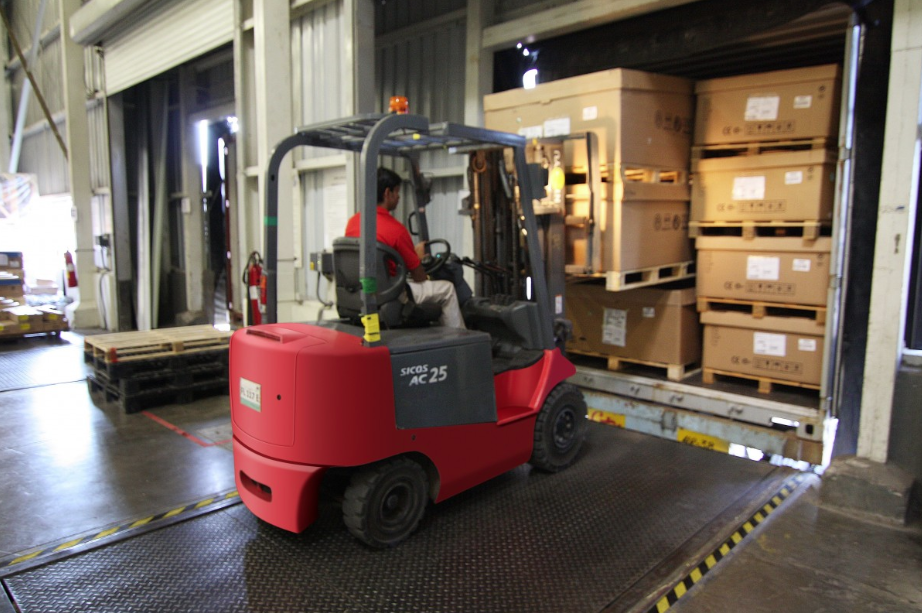 red forklift loading a freight truck bed