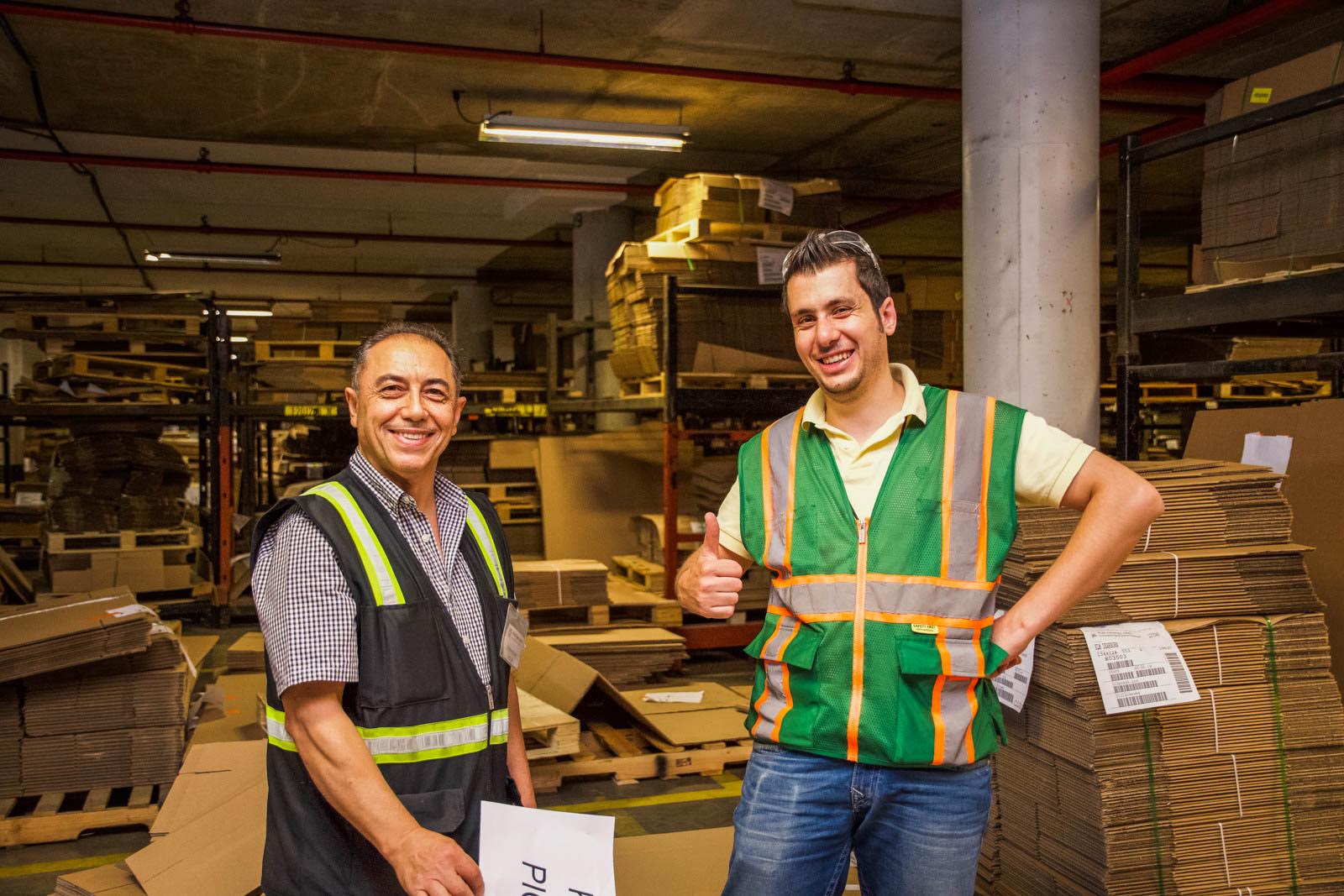 Smiling warehouse employees give a thumbs up